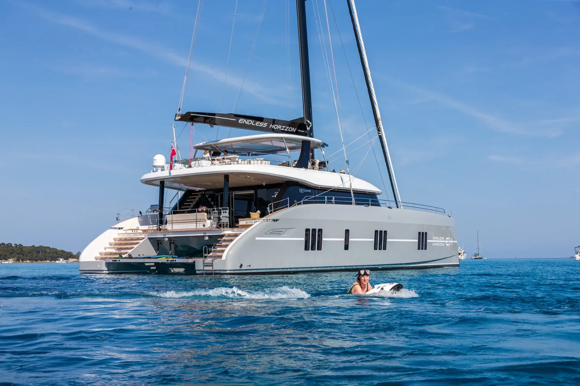 A guest on a Seabob alongside Endless Horizon II at anchor in calm blue water