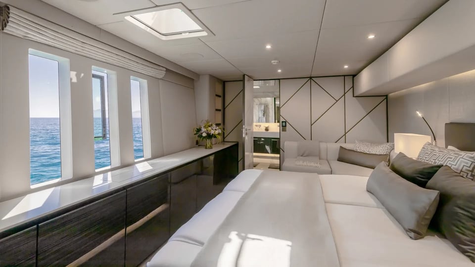 Guest cabin with settee, hull windows and ensuite beyond