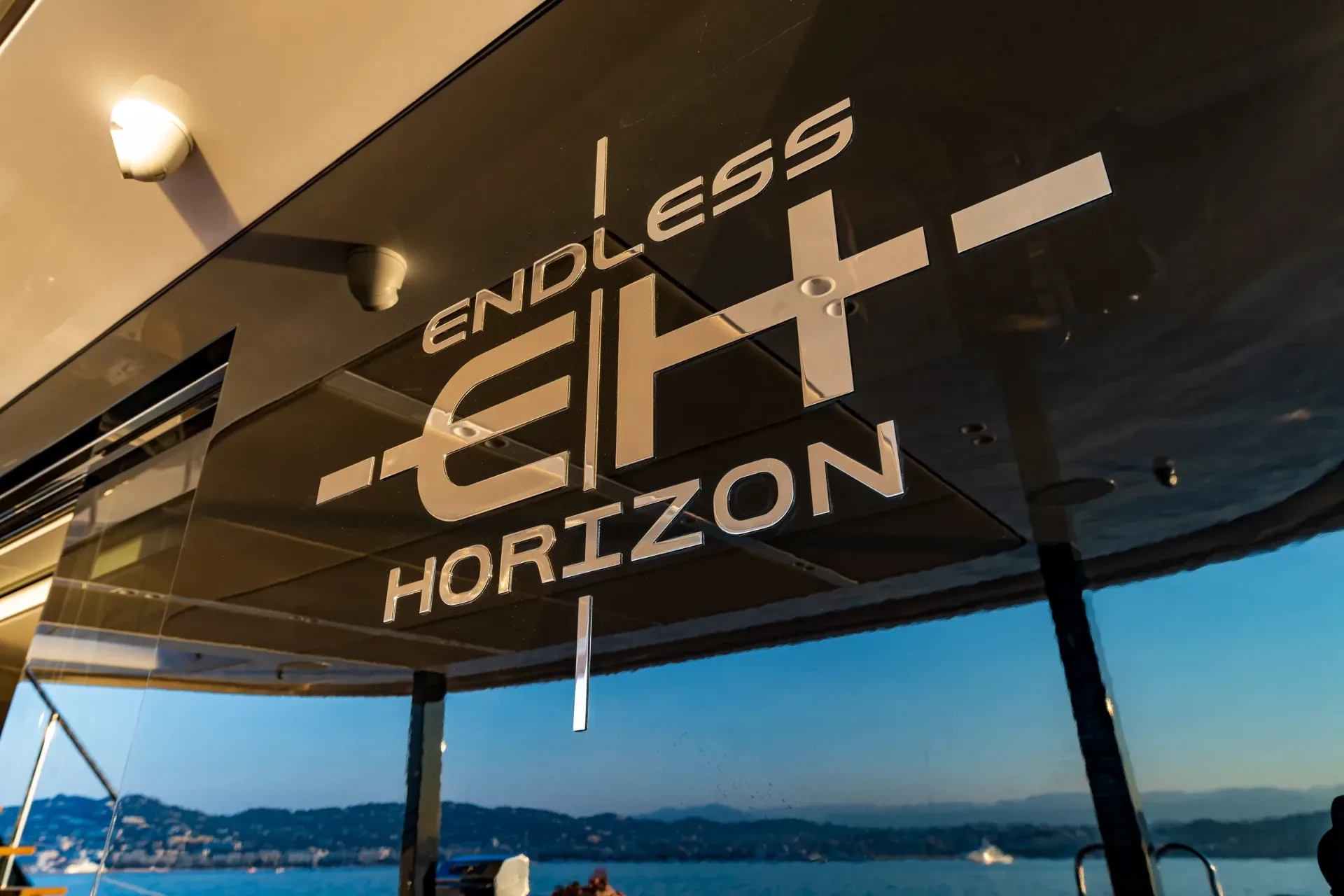Polished Endless Horizon nameplate on the gloss transom at dusk