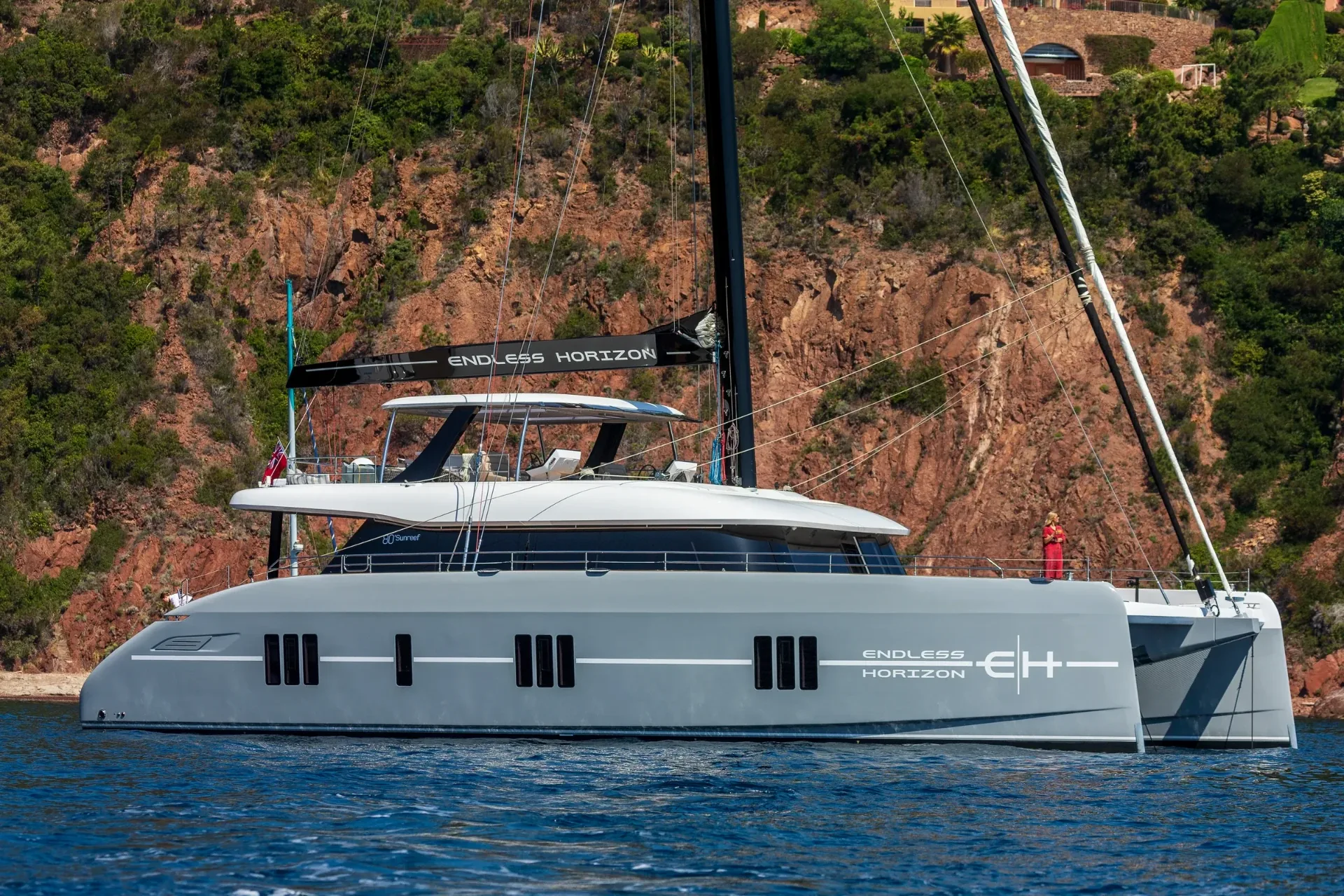 Full profile of Endless Horizon II at anchor beneath the red rock of the Esterel
