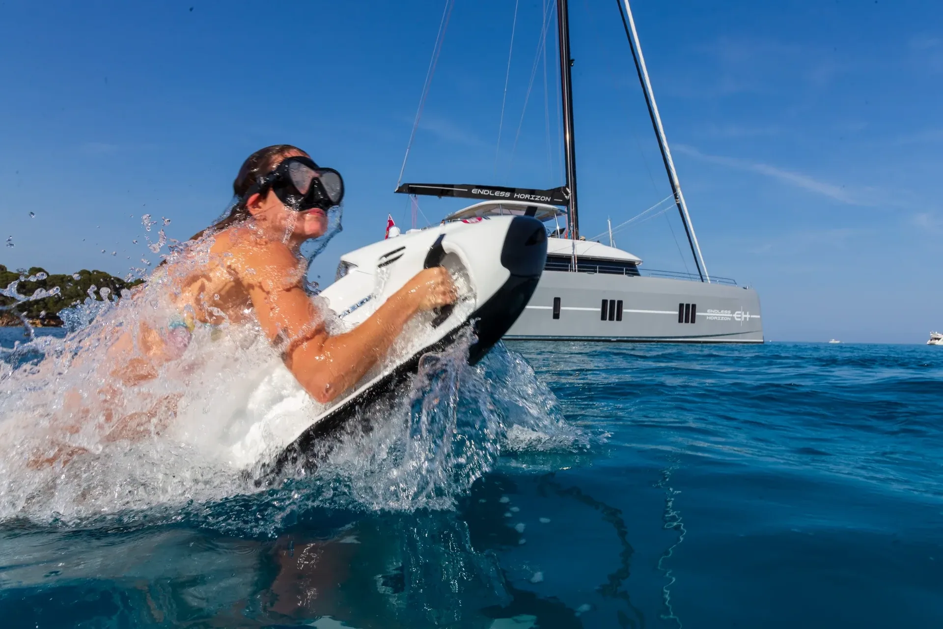 Guest carving a Seabob through spray with the yacht behind