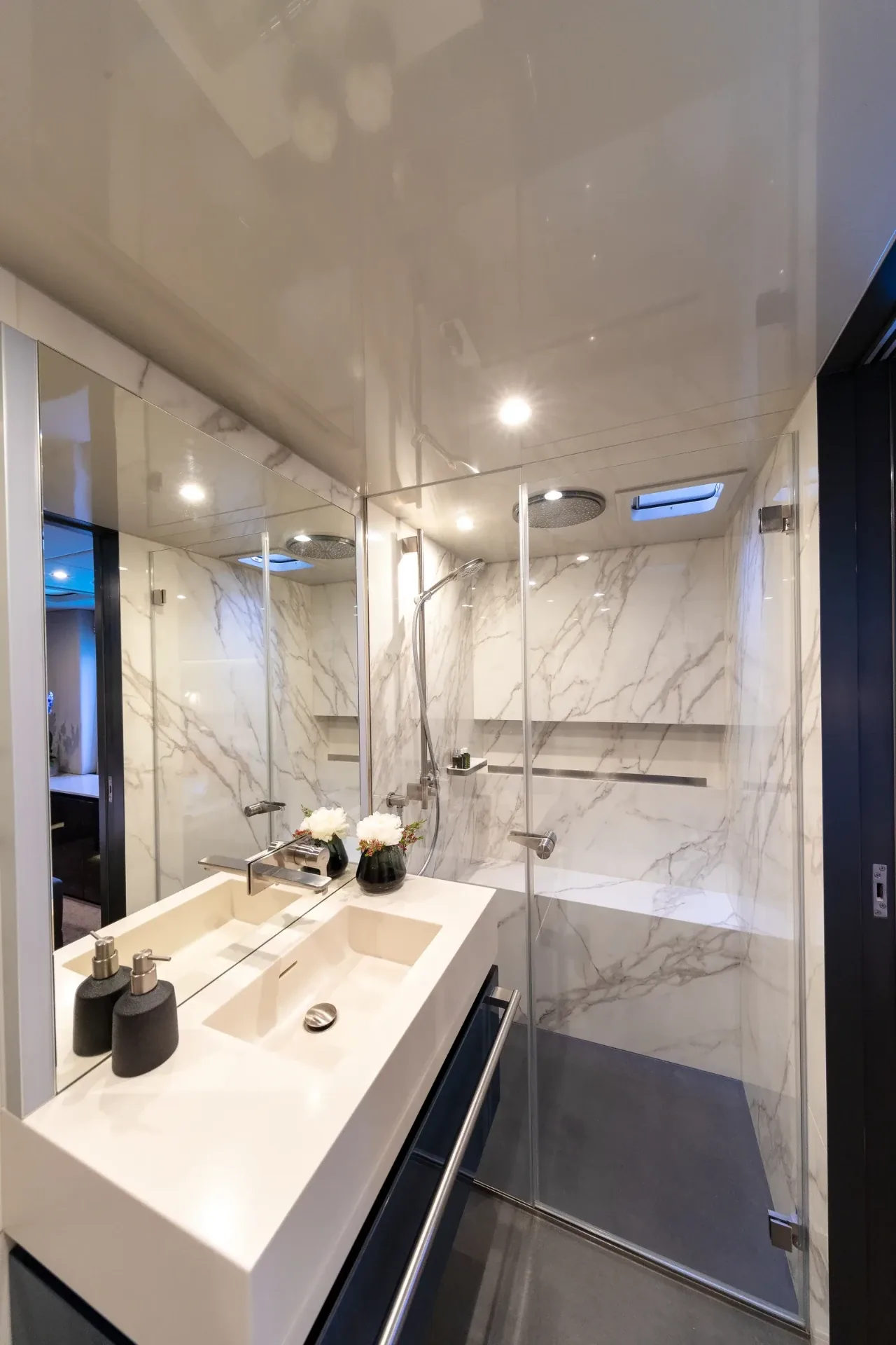 Guest ensuite in book-matched marble with a rain shower and mirrored vanity