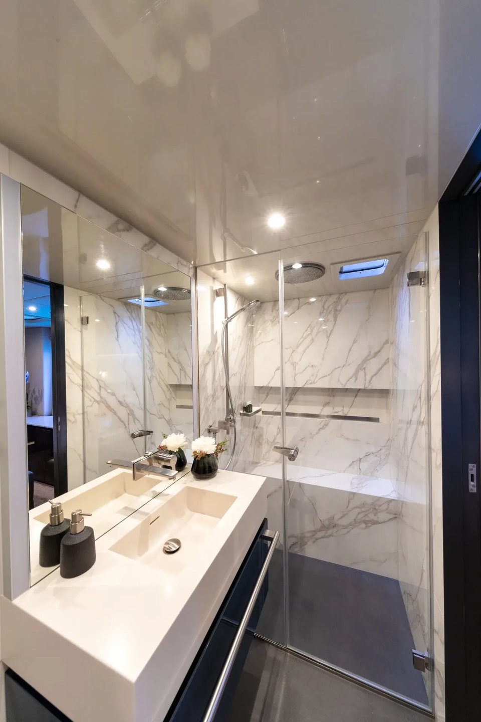 Guest ensuite in book-matched marble with a rain shower and mirrored vanity