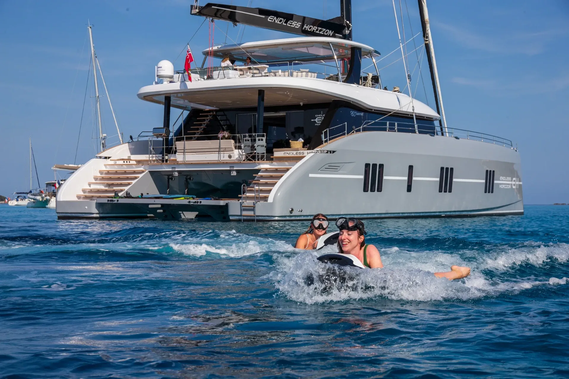 Two guests riding Seabobs off the swim platform, dive gear laid out on the transom