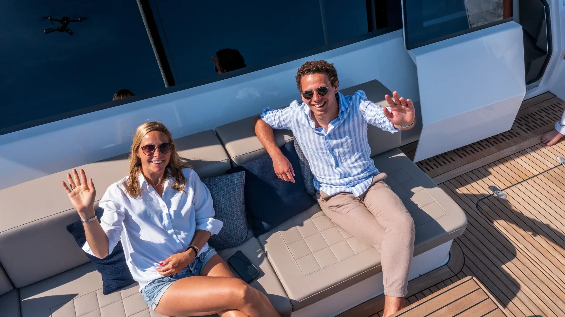Guests waving up at the drone from the forward cockpit sofa