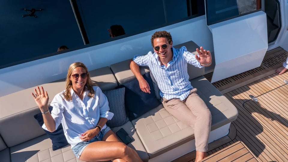 Guests waving from the deck of Endless Horizon II at anchor