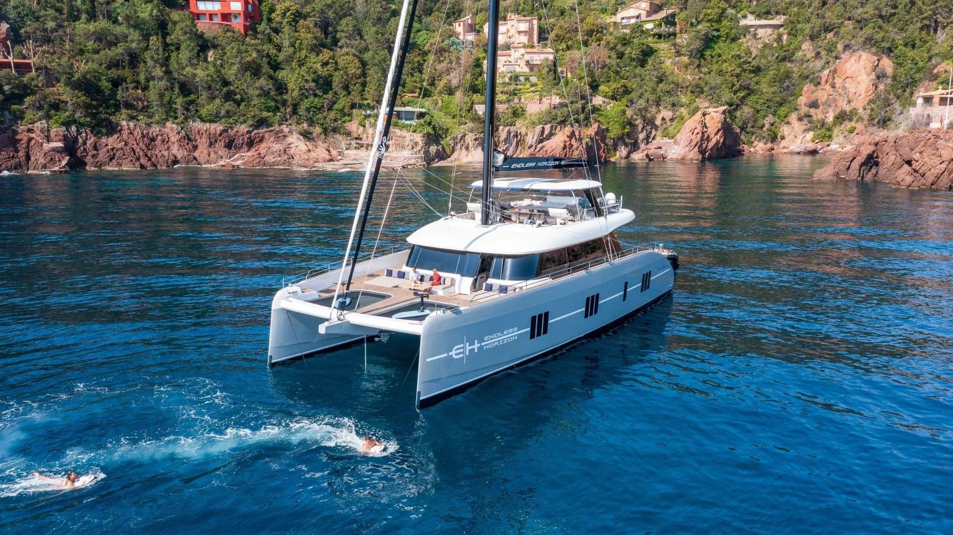 Endless Horizon II at anchor in a red-rock cove with guests swimming alongside