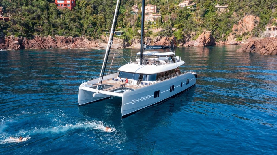 Endless Horizon II at anchor in a red-rock cove with guests swimming alongside