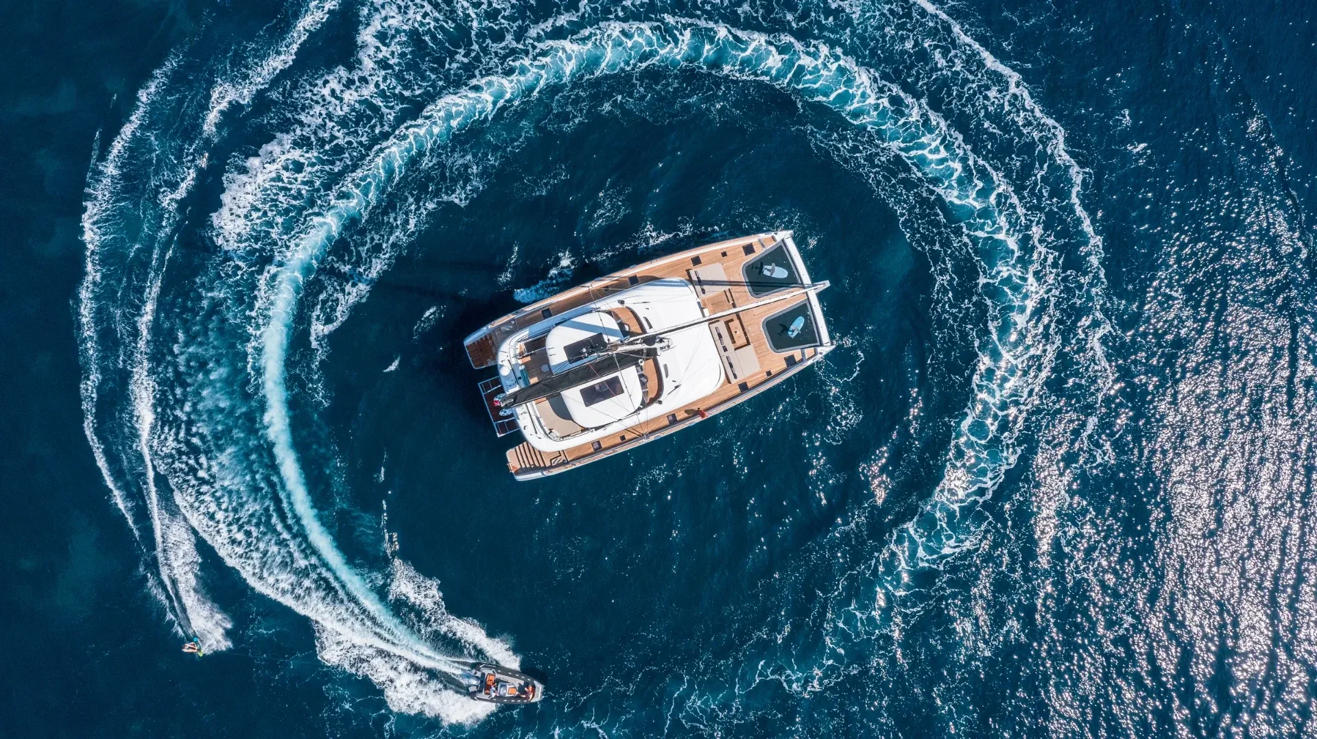 Top-down aerial of the catamaran ringed by tender wake circles