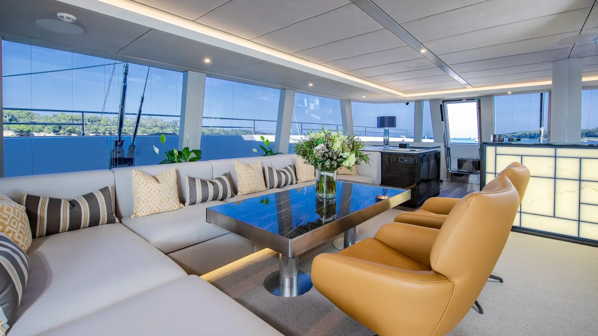 Salon lounge with a corner sofa, leather swivel chairs and wraparound glass