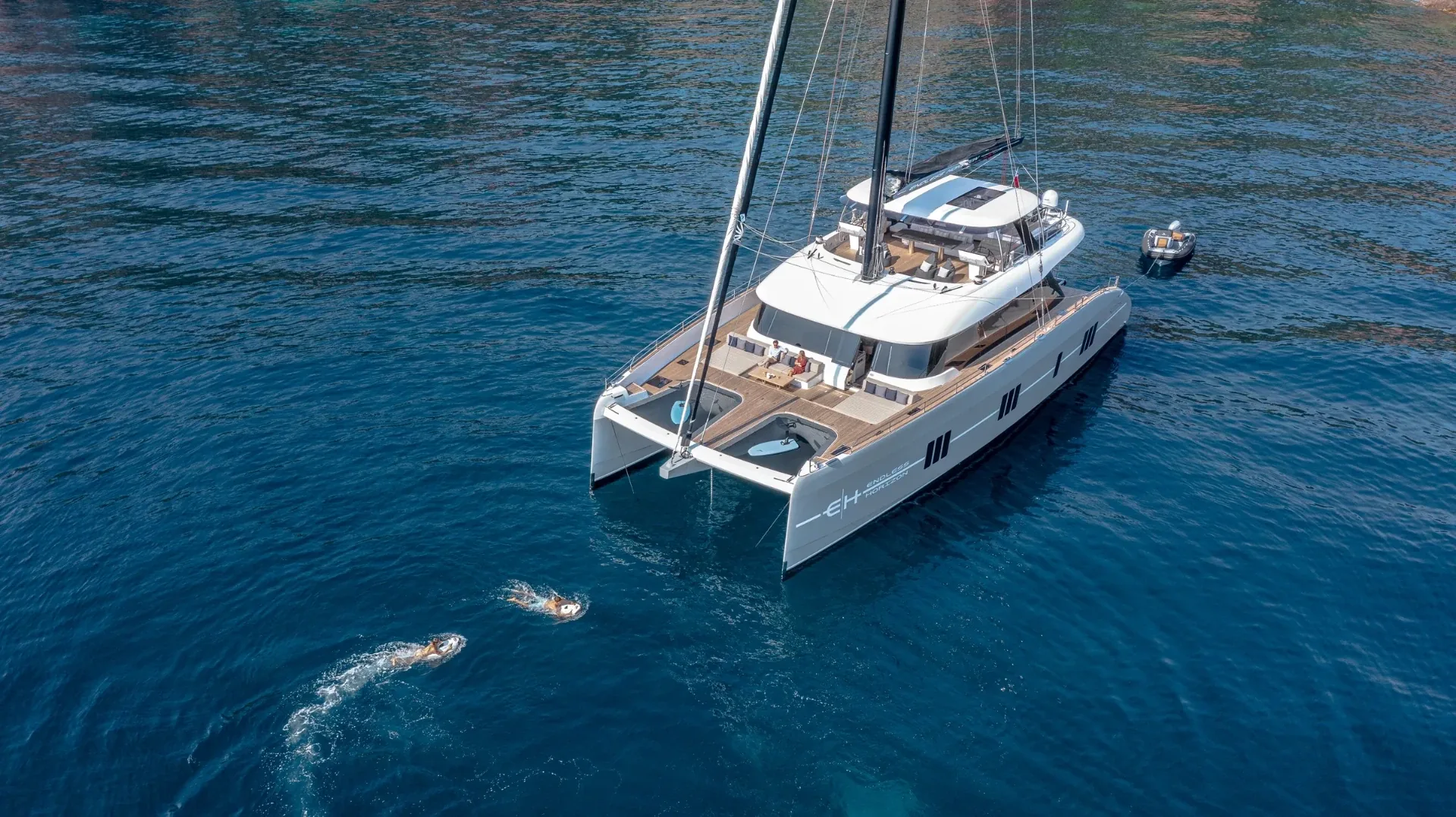 Aerial view of guests swimming toward Endless Horizon II at anchor in deep blue water