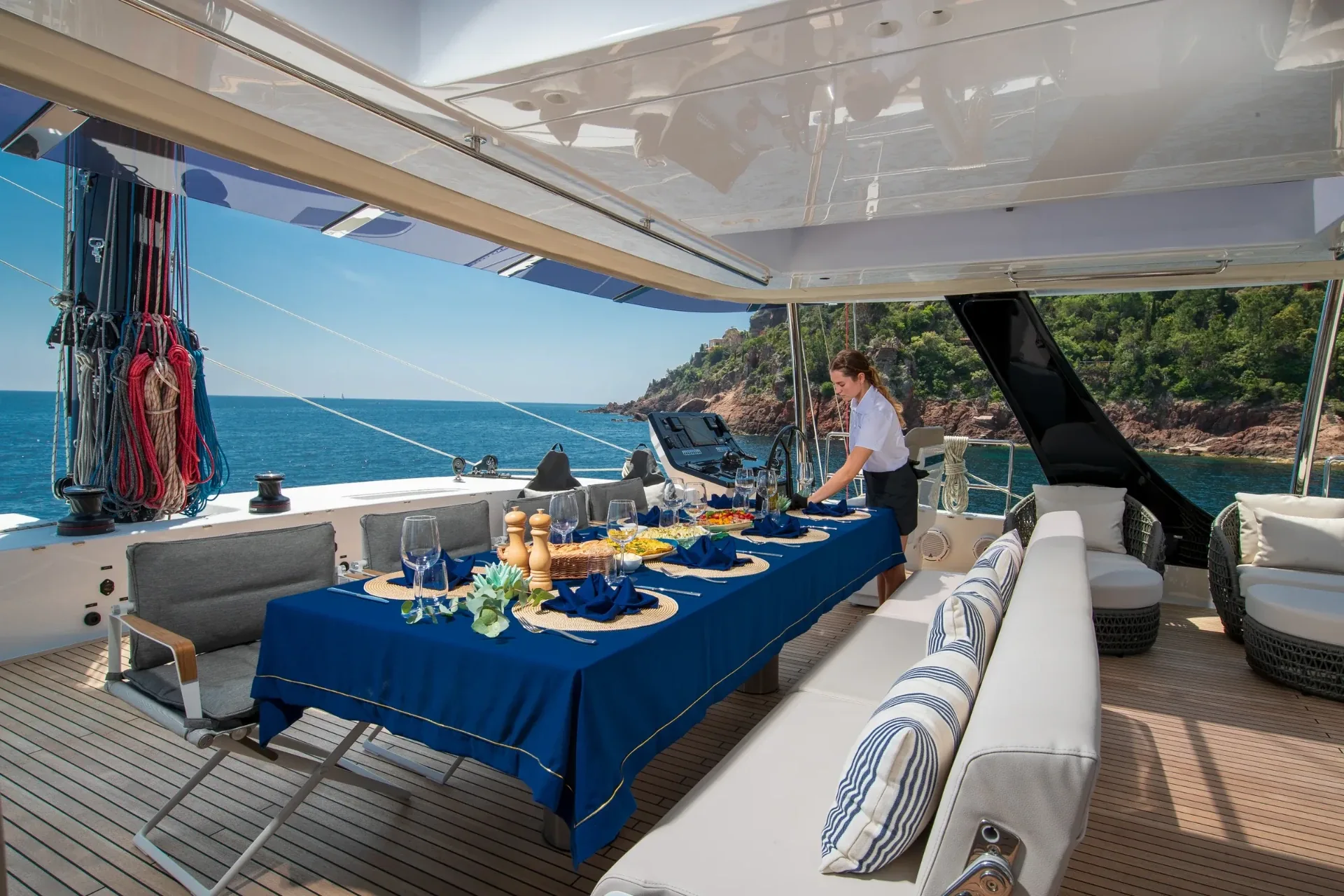 Long forward table dressed in blue linen for lunch, crew finishing the setting